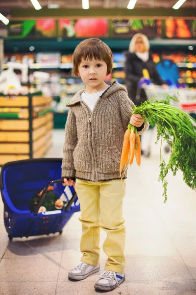 Bonito menino pequeno e orgulhoso ajudando com compras de supermercado, saudável — Fotografia de Stock