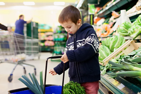 Симпатичный маленький и гордый мальчик, помогающий с покупками продуктов, здоровый — стоковое фото