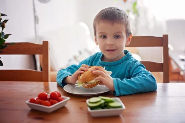 Beautiful little boy, eating sandwich at home, vegetables on the — Stock Photo, Image