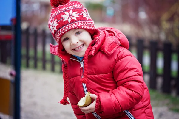 Kolorowy portret ładny mały chłopiec, jedzenie gruszka na si — Zdjęcie stockowe