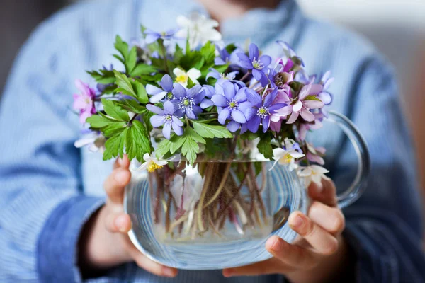 Malé ruce, skleněná váza s lesní jarní květ bouqu — Stock fotografie