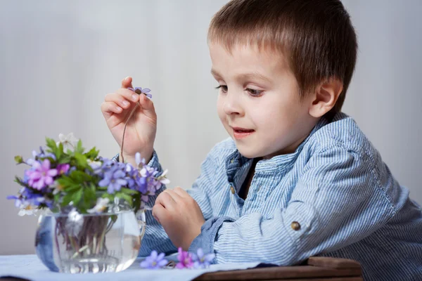 Adorabile bambino, guardando vaso con mazzo di fiori primaverili — Foto Stock