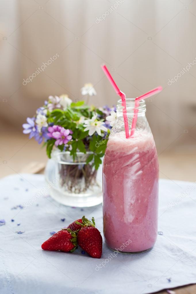 Strawberry smoothie freshly made in a jar with a lined straw, fo