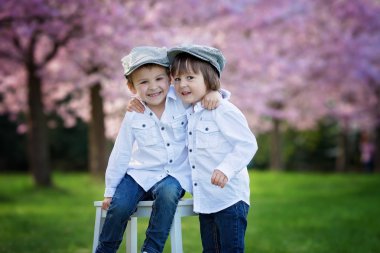 Bahar öğleden sonra kiraz çiçeği bahçesinde iki sevimli çocuk