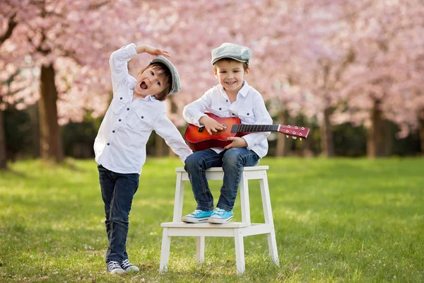 Dois meninos caucasianos adoráveis em um jardim de cerejeira florescente, pl — Fotografia de Stock