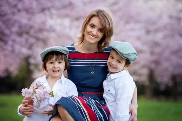 Beautiful kids and mom in spring park, flower and present. Mothe — Stock Photo, Image