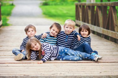 Five adorable kids, dressed in striped shirts, hugging and smili
