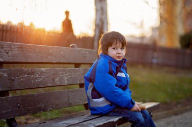 Çikolata yeme bir bankta oturan sevimli küçük çocuk,
