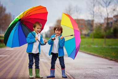 Oyun iki sevimli küçük çocuklar, yağmurlu bir günde, bir parkta yürüyüş