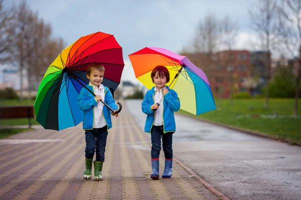 Two adorable little boys, walking in a park on a rainy day, play — Stock Photo, Image