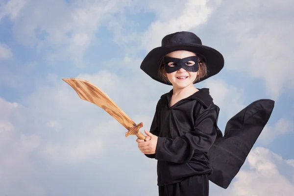 Superhero child with sward and costume on a blue sky background — Stock Photo, Image