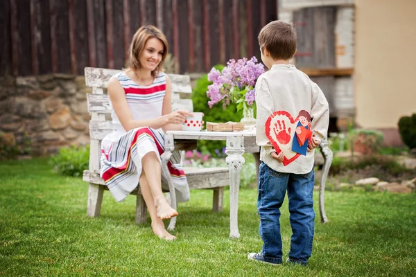 Beautiful mom, having coffee in a backyard, young cute child giv — Stock Photo, Image