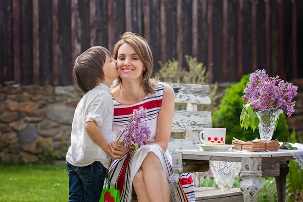 Beautiful mom, having coffee in a backyard, young cute child giv — Stock Photo, Image