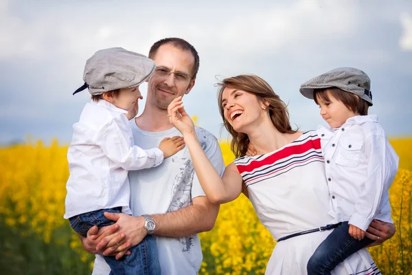 Vierköpfige Familie, Mutter, Vater und zwei Jungen, in einem Rapsfeld — Stockfoto