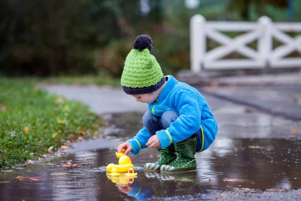 小さな男の子が、泥だらけの水たまりにジャンプ — ストック写真