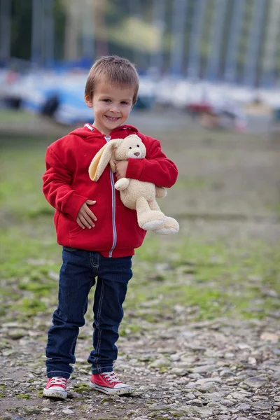 Mignon garçon, tenant ours en peluche sur un port — Photo