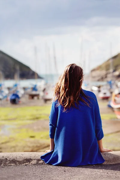 Jeune femme, assise sur un port, regardant l'océan — Photo