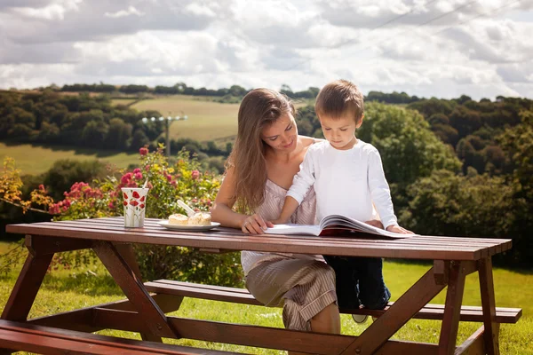 Mãe e filho, lendo um livro ao ar livre, dia de verão — Fotografia de Stock