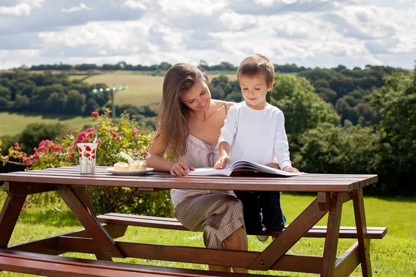 Mutter und Sohn lesen draußen ein Buch, Sommertag — Stockfoto