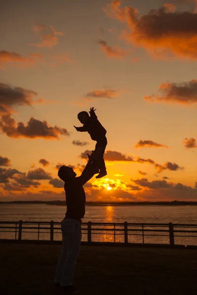 ビーチ、シルエット s の空気に彼の子供を投げての父 — ストック写真