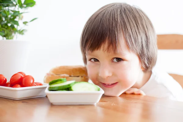 Beautiful little boy, eating sandwich at home, vegetables on the — Stock Photo, Image