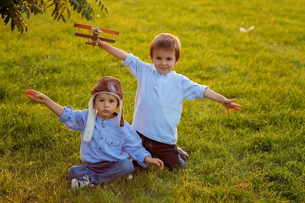 Два мальчика, играющие с самолетом на закате в парке — стоковое фото