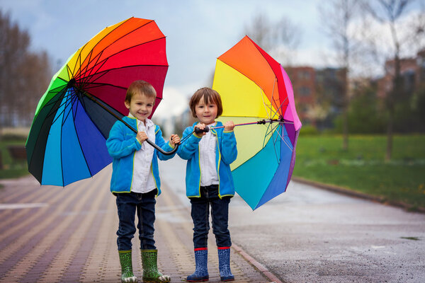 Two adorable little boys, walking in a park on a rainy day, play