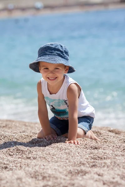 Lindo chico, jugando con guijarros en la playa —  Fotos de Stock
