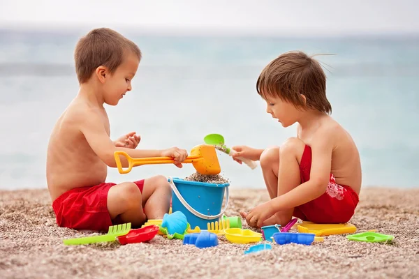 Duas crianças giras, brincando na areia na praia — Fotografia de Stock