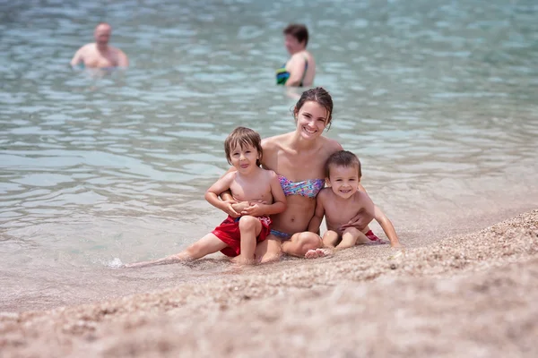 Fiatal anya a strandon neki gyerekekkel — Stock Fotó