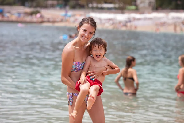 Fiatal anya a strandon neki gyerekekkel — Stock Fotó