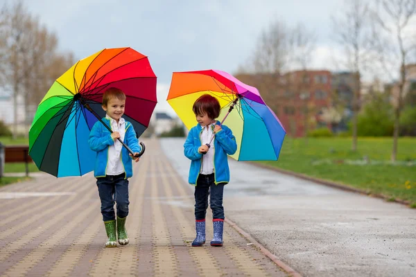 Two adorable little boys, walking in a park on a rainy day, play Royalty Free Stock Photos
