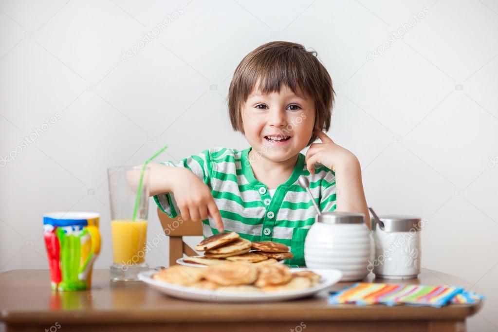 Sweet little caucasian boy, eating pancakes