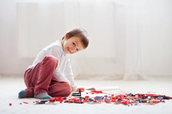 Niño pequeño jugando con un montón de bloques de plástico de colores en el interior —  Fotos de Stock