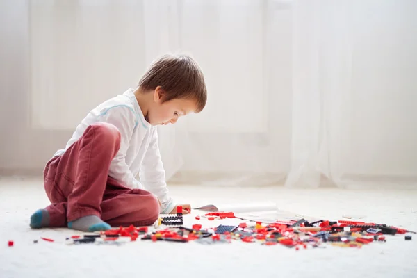 Kleines Kind spielt drinnen mit vielen bunten Plastikklötzen — Stockfoto