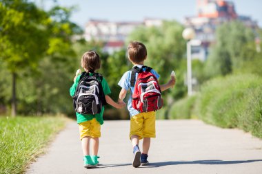 İki sevimli çocuk AWA yürüyüş renkli giysiler ve sırt çantaları,