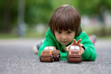 Funny little boy playing with car of chocolate, outdoor clipart