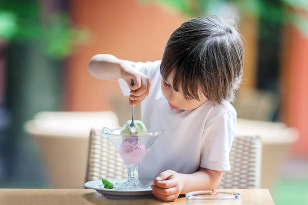 Menino bonito, comendo sorvete em um restaurante — Fotografia de Stock