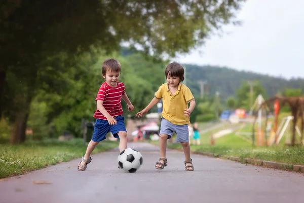 Dois miúdos giros, a jogar futebol juntos, no Verão. — Fotografia de Stock