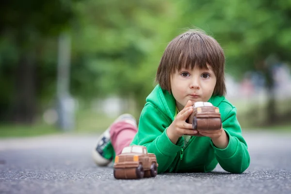 チョコレート、屋外の車で遊んで面白い少年 — ストック写真