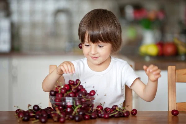 Carino bambino, mangiare ciliegie a casa in cucina, fare — Foto Stock