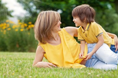 Young beautiful mom and her cute little boy, relaxing and having