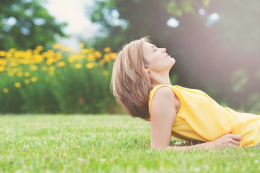 Beautiful young attractive woman, lying on the grass in park
