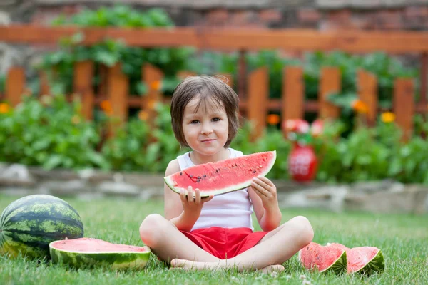 Мальчик, есть арбуз в саду, летом — стоковое фото