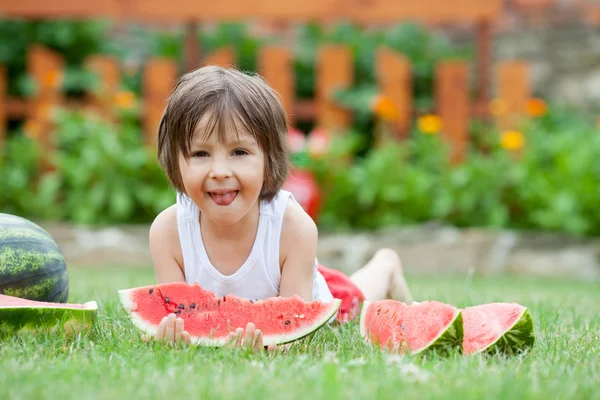 少年は、庭、夏にスイカを食べる — ストック写真