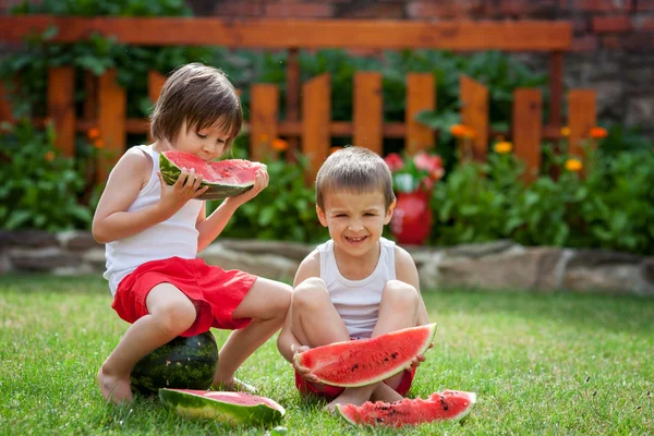 Due ragazzi, che mangiano anguria in giardino, estate — Foto Stock