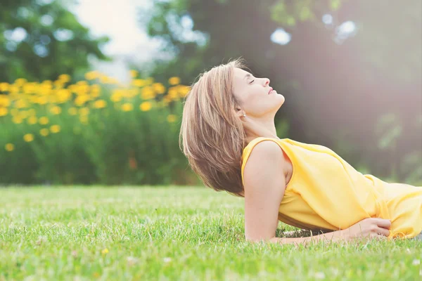 Beautiful young attractive woman, lying on the grass in park — Stockfoto