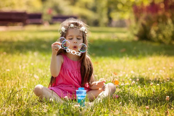 Красивый портрет милой милой маленькой девочки, дующей мыльным пузырем — стоковое фото
