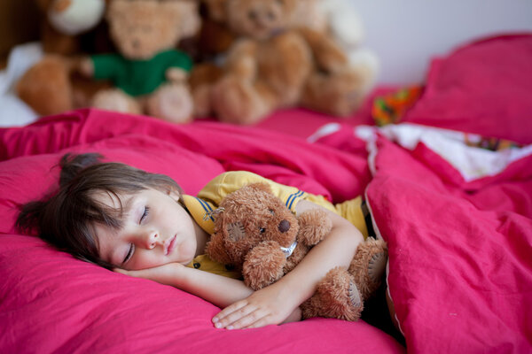 Sweet little boy, sleeping in the afternoon with his teddy bear