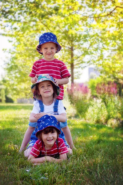 Tři děti v parku, jeden nad druhým, stojící, s úsměvem — Stock fotografie